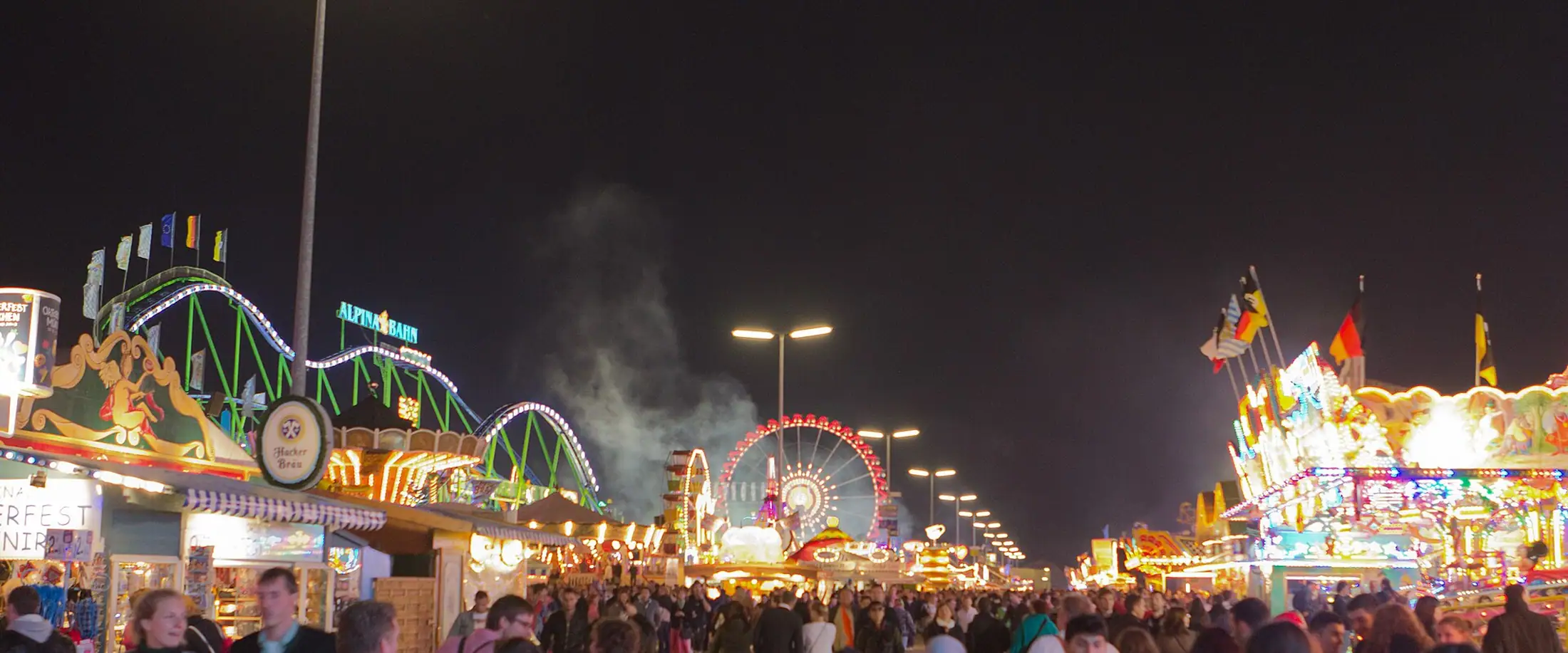 Volksfest bei Nacht mit beleuchteten Fahrgeschäften